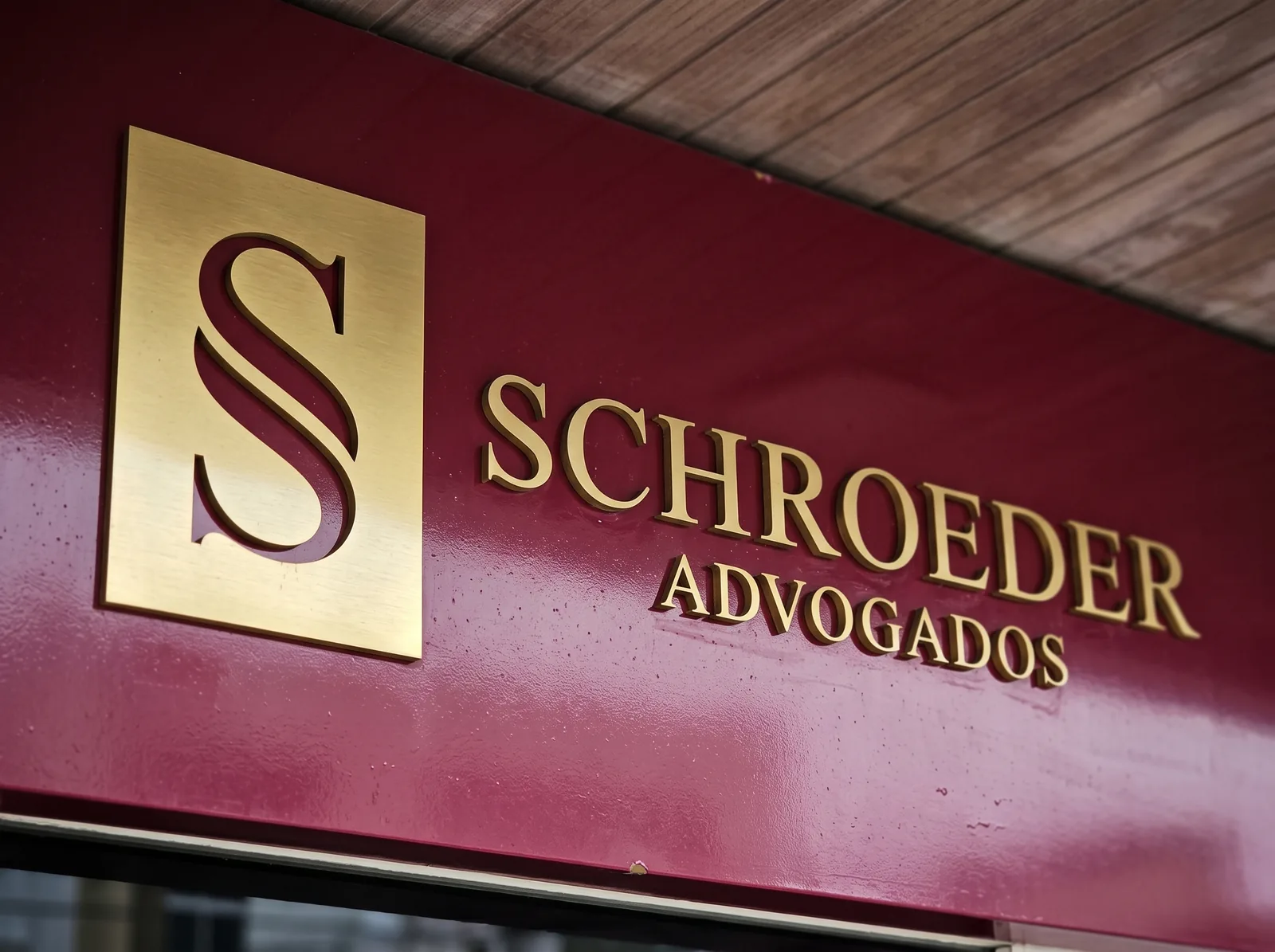 Logo do Schroeder Advogados em dourado sobre bordô, na fachada do escritório